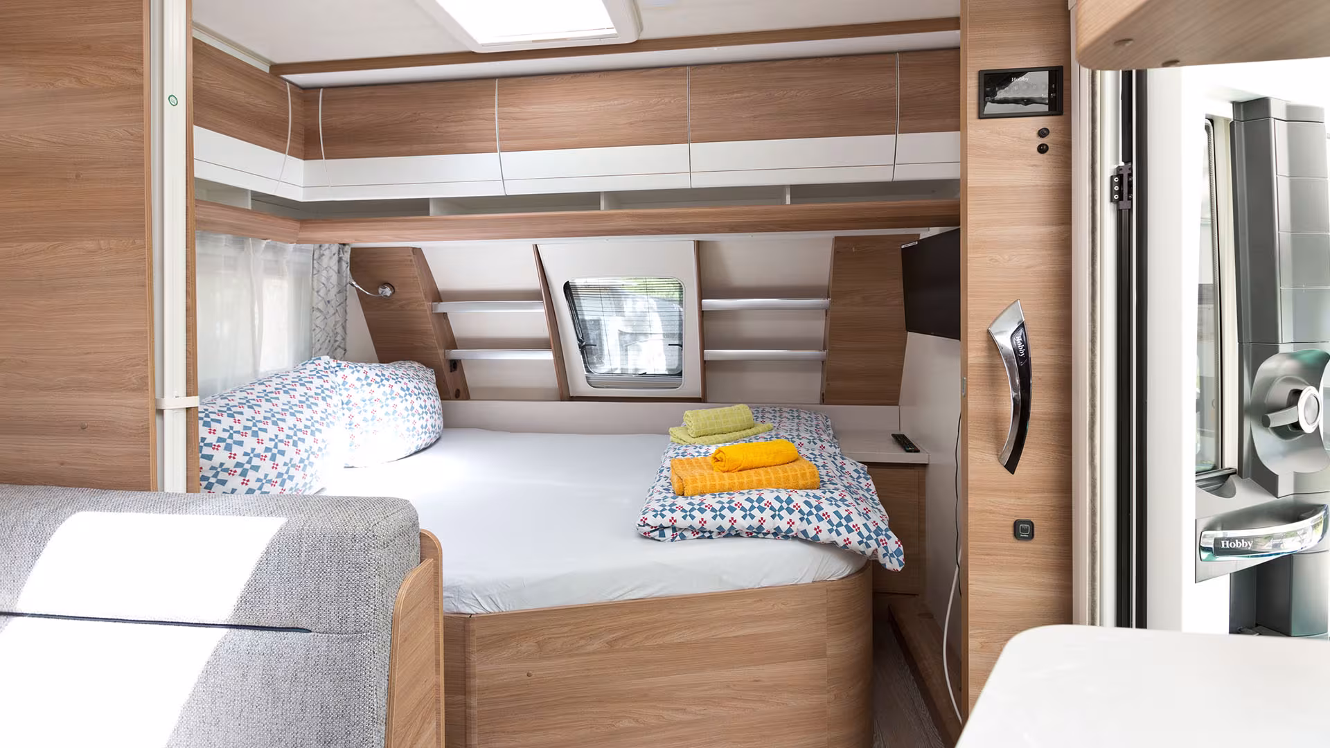 Schlafbereich mit Bett und Kühlschrank im Miet-Wohnwagen
